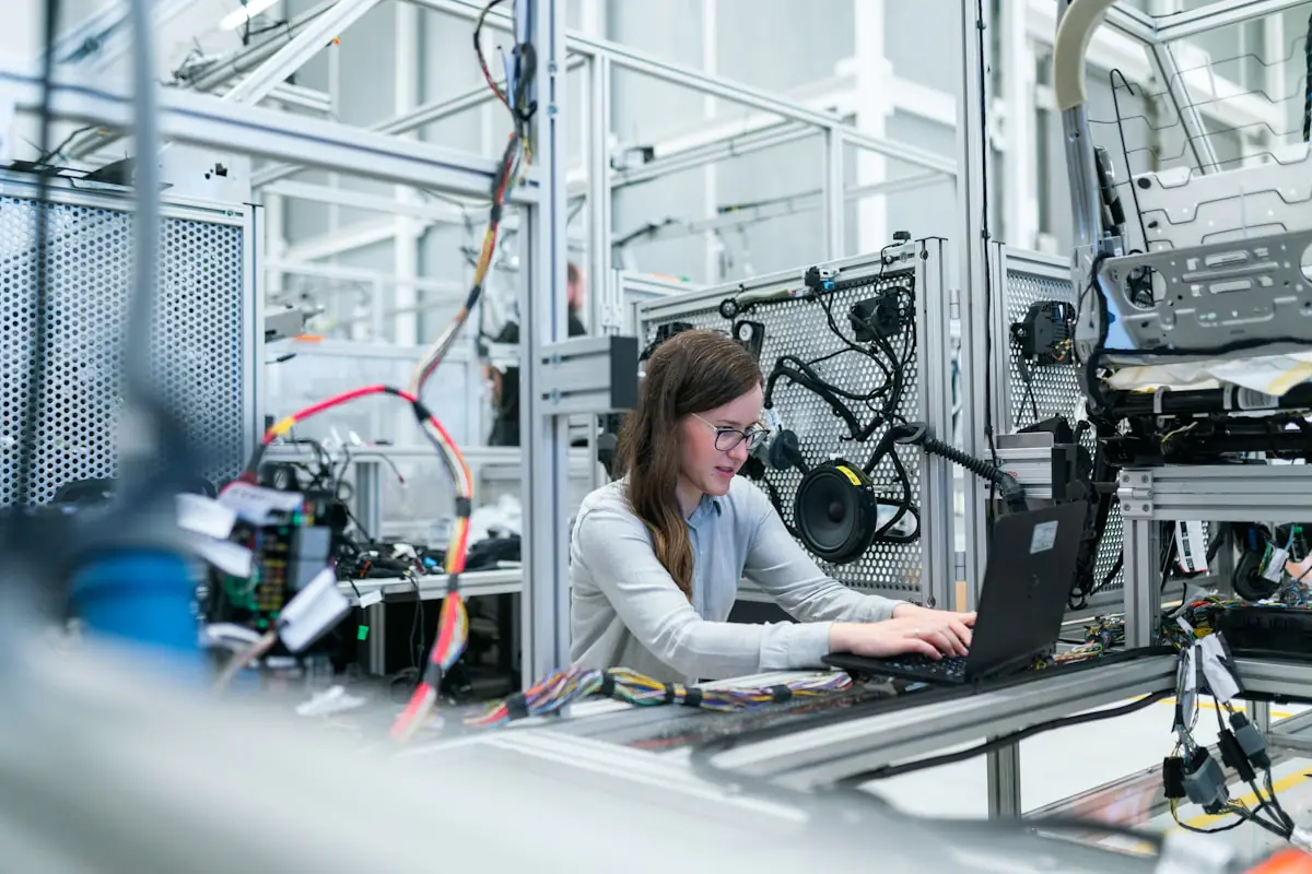 Engineer integrating production systems with laptop in manufacturing facility